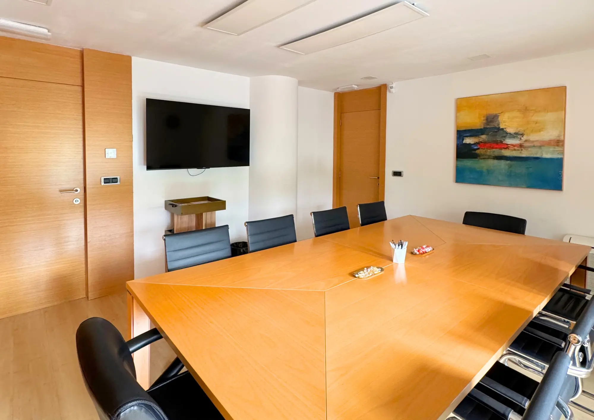 Sala de juntas con mesa de madera y pantalla
