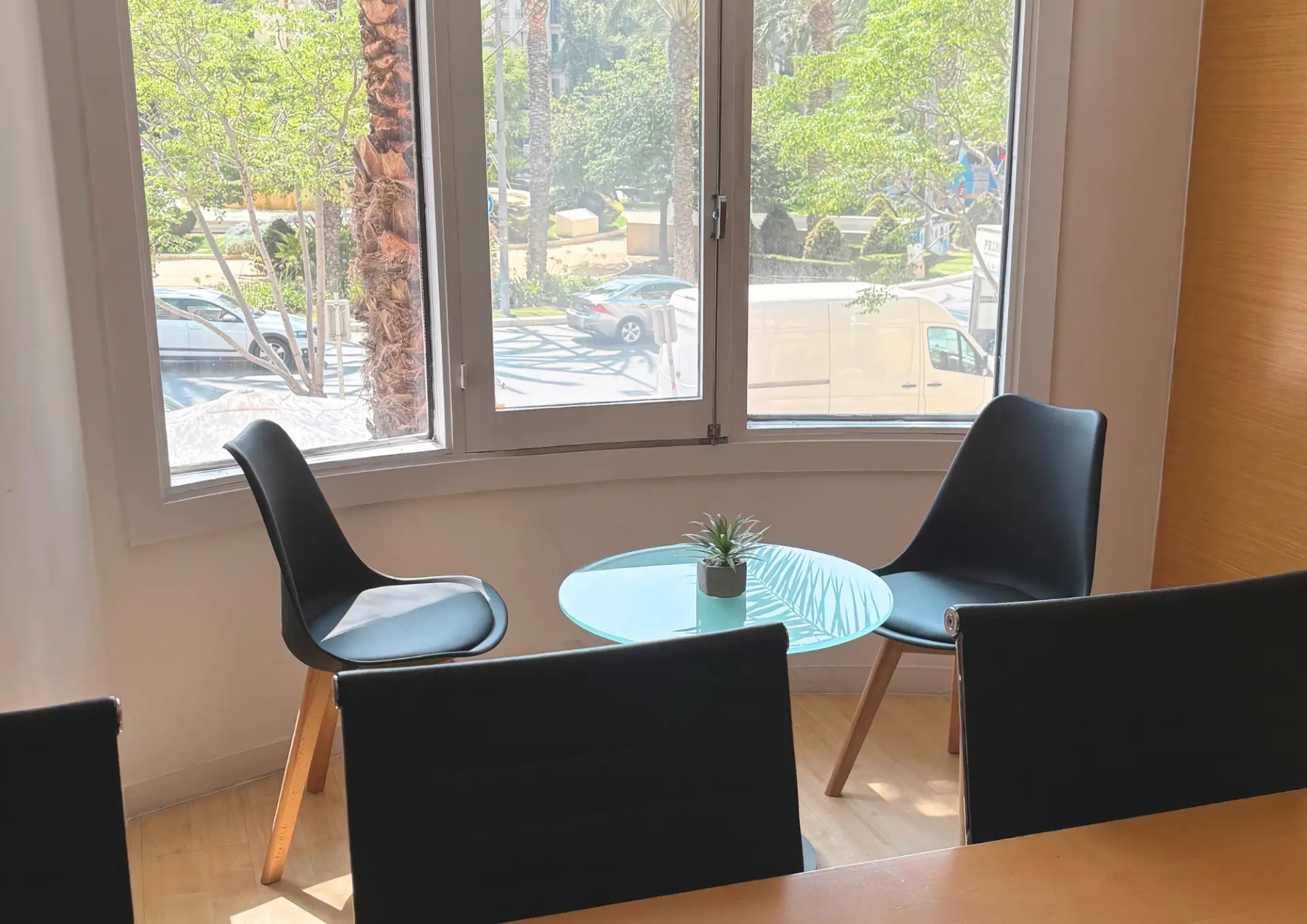 Zona de reuniones informal con mesa de cristal junto a ventanales